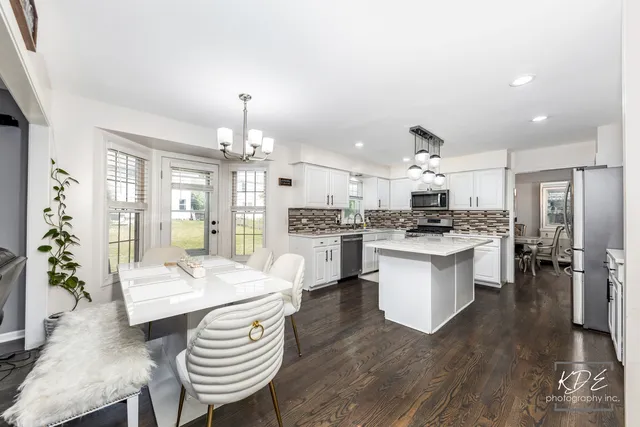 a large open kitchen with a refrigerator a stove a sink dishwasher and white cabinets with wooden floor