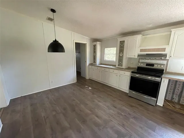 a kitchen with stainless steel appliances granite countertop a refrigerator a sink dishwasher a stove and white countertops with wooden floor