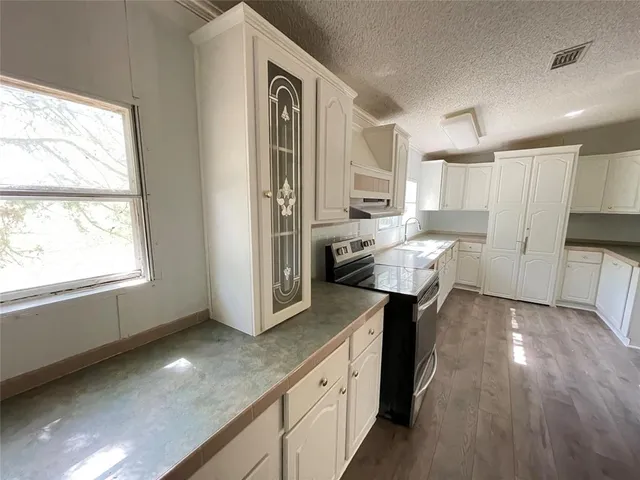 a kitchen with white cabinets and sink