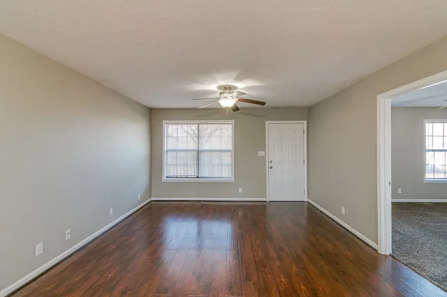 a view of an empty room with wooden floor and a window