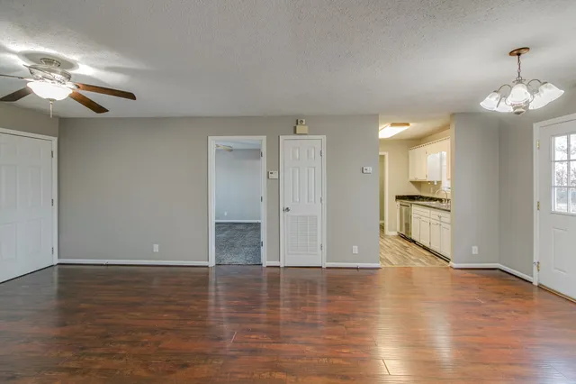a view of a livingroom with wooden floor and a kitchen