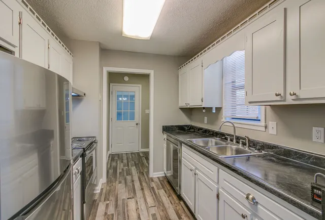 a kitchen with granite countertop a sink stove and refrigerator