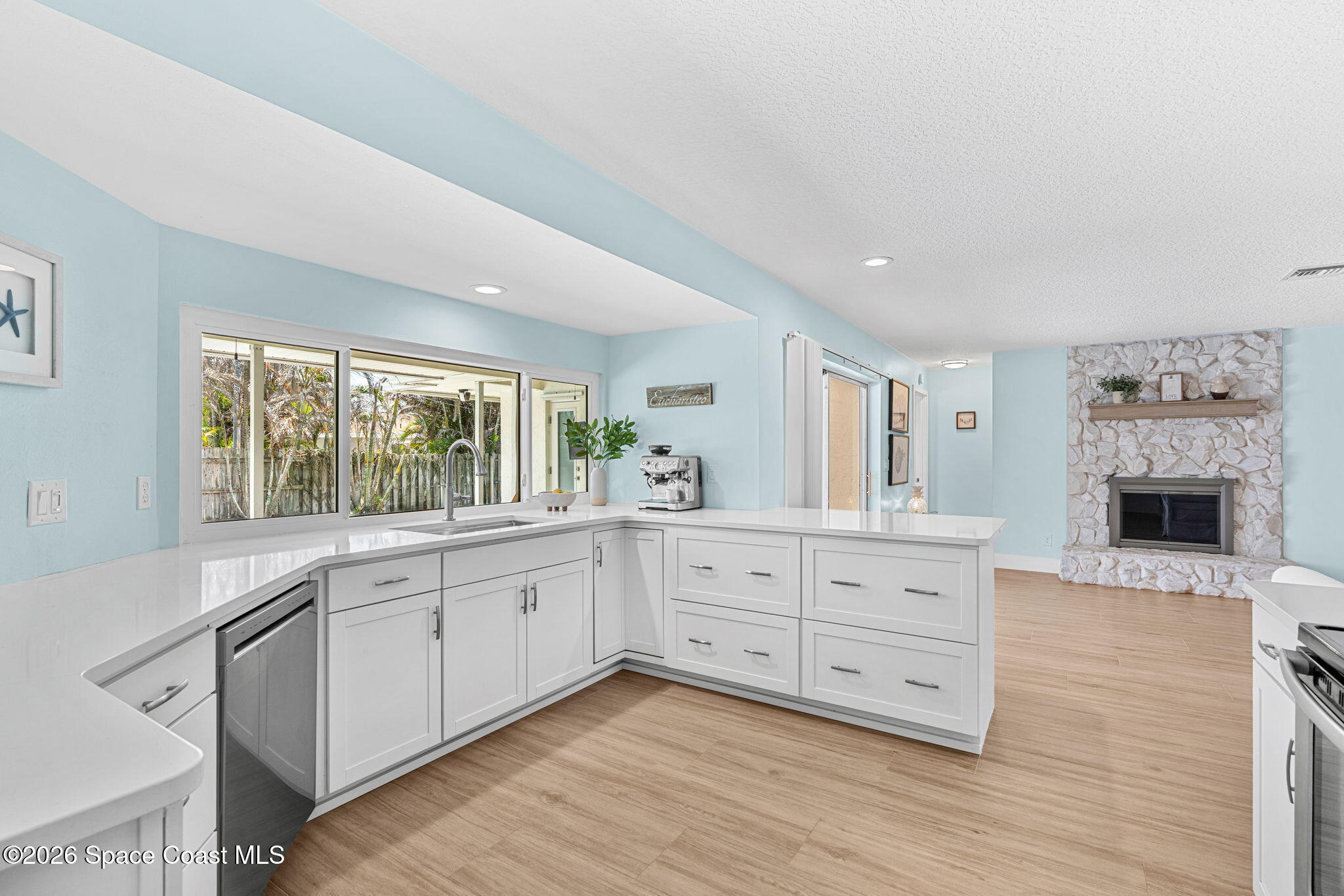 429 Rio Lane Indialantic, FL 32903 - Photo 17 of 50 a large white kitchen with granite countertop a stove a sink and white cabinets with wooden floor