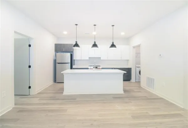 a view of kitchen with kitchen island white cabinets and stainless steel appliances