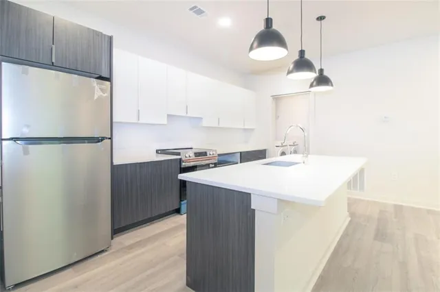 a kitchen with a sink a refrigerator a stove and white cabinets