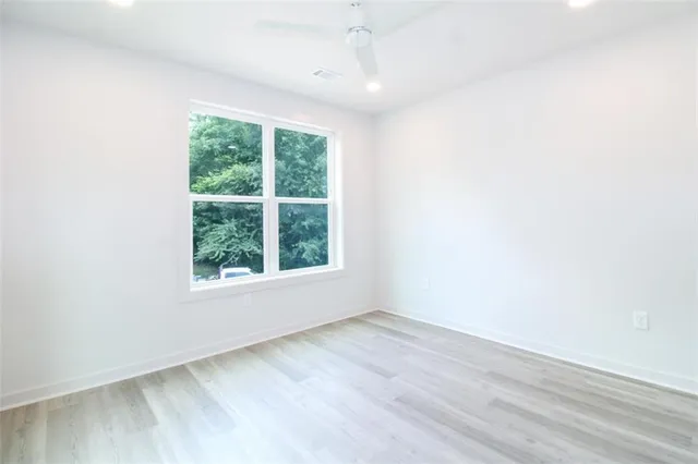 an empty room with wooden floor and windows