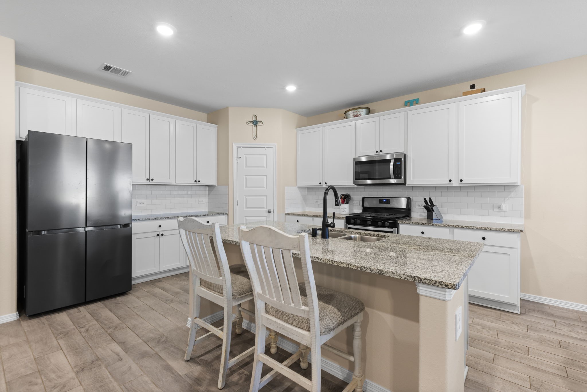 14499 Sunny Bend Way Conroe, TX 77303 - Photo 11 of 41 a kitchen with stainless steel appliances granite countertop a stove a sink a microwave a refrigerator and white cabinets