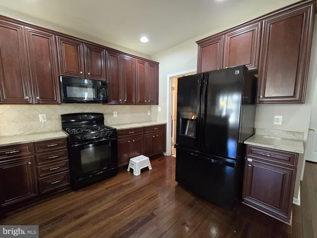 a large kitchen with stainless steel appliances a large counter top a stove and a refrigerator