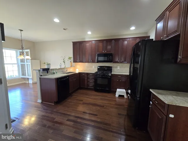 a kitchen with kitchen island granite countertop wooden floors stainless steel appliances a sink and a window