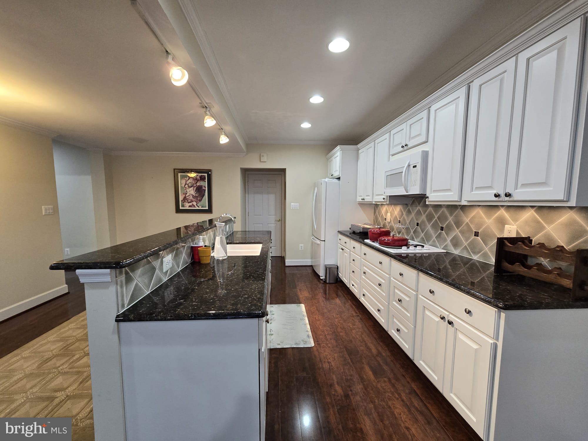 25170 Fortitude Terrace Chantilly, VA 20152 - Photo 35 of 50 a kitchen with granite countertop a stove a sink a refrigerator and white cabinets with wooden floor
