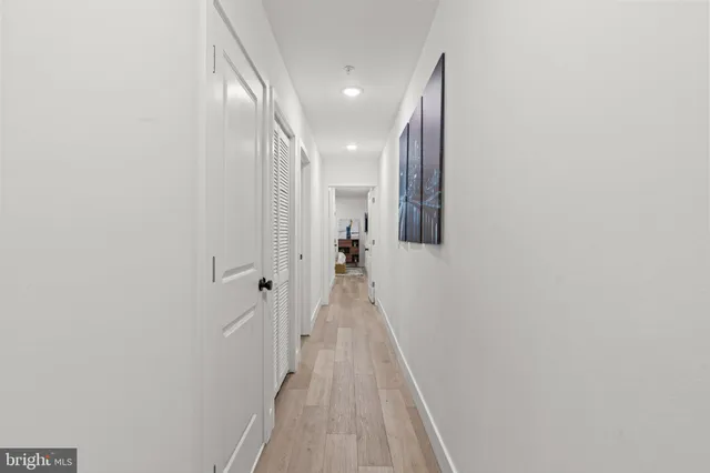 a view of a hallway with wooden floor and a bathroom