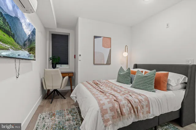 a bedroom with a bed a desk and chair with wooden floor