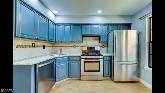a kitchen with stainless steel appliances granite countertop a stove a sink dishwasher and a refrigerator with wooden floor