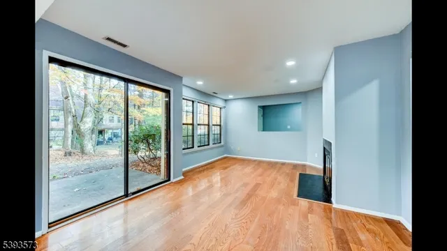 a view of an empty room with wooden floor fire place