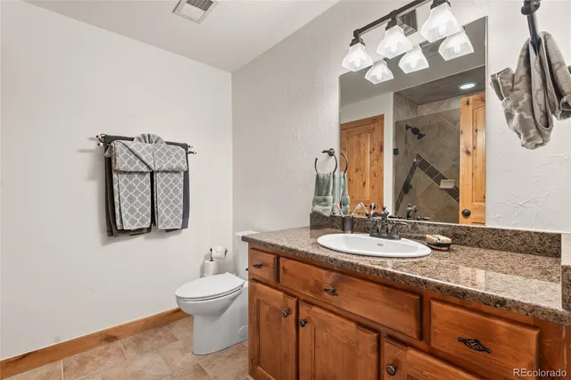 a bathroom with a granite countertop sink a toilet and mirror