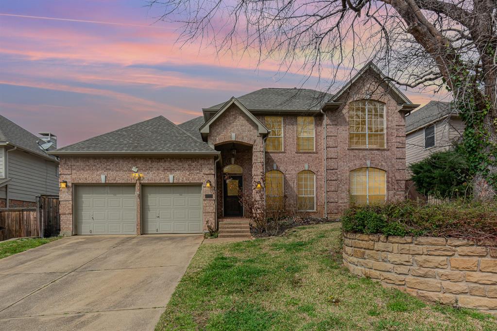 2144 Brookgate Drive Grapevine, TX 76051 - Photo 1 of 1 Traditional home featuring an attached garage, brick siding, driveway, and roof with shingles