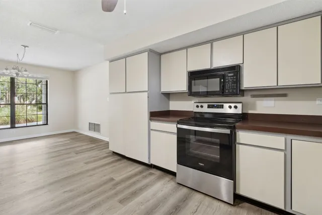 a kitchen with stainless steel appliances granite countertop a stove a microwave and white cabinets