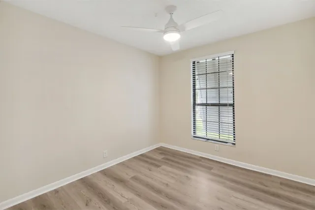 an empty room with windows and ceiling fan
