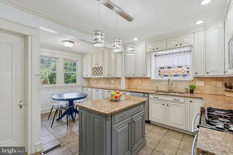 a kitchen with a stove a sink dishwasher and white cabinets with wooden floor