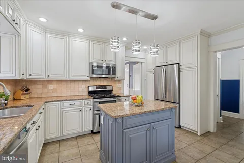 a kitchen with stainless steel appliances granite countertop a refrigerator a sink dishwasher a stove and white cabinets with wooden floor