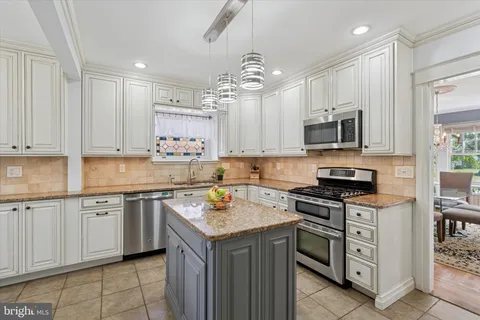 a kitchen with kitchen island granite countertop a sink counter top space appliances and cabinets