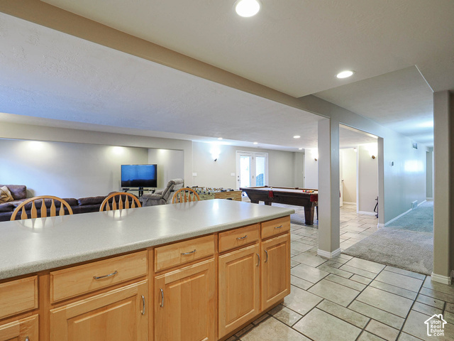 11779 South Stone Ridge Court Ridge West Riverton, UT 84065 - Photo 58 of 85 Spacious lower-level area featuring a large island with light wood cabinetry and a light-toned countertop, recessed lighting, and a combination of tile and carpet flooring
