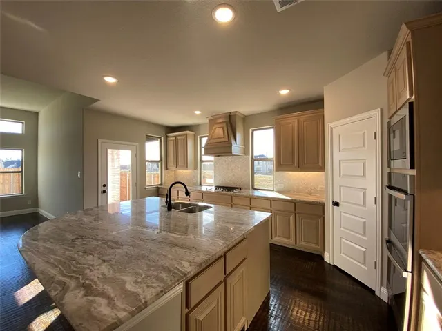 a kitchen with kitchen island granite countertop a sink a counter space and cabinets