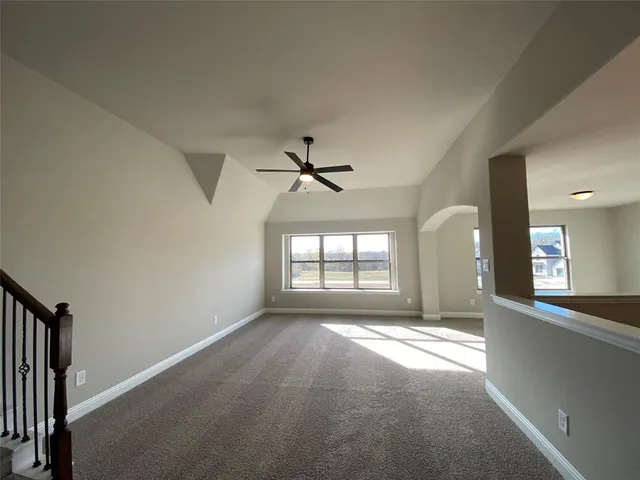 a view of n empty room with window and a kitchen
