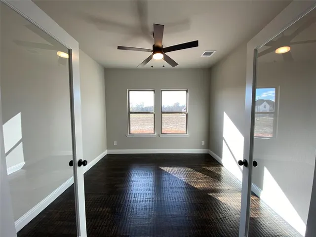 a view of empty room with wooden floor and fan