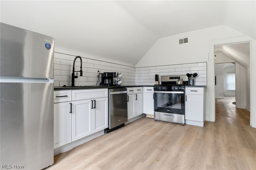 3326 East Overlook Road Cleveland Heights, OH 44118 - Photo 21 of 29 Kitchen featuring stainless steel appliances, white shaker-style cabinetry, dark countertops, a white subway tile backsplash, and light wood-finish flooring