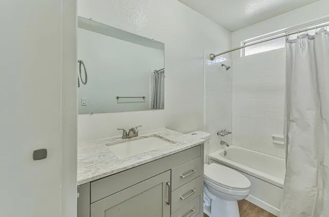 a bathroom with a granite countertop sink a toilet and shower