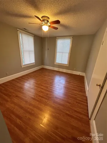 a view of an empty room with window and wooden floor