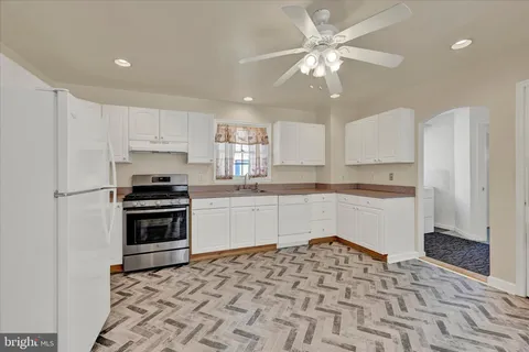 a kitchen with granite countertop a refrigerator stove and white cabinets
