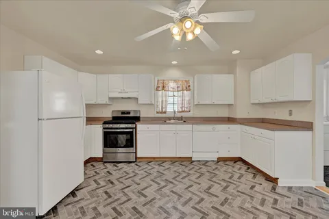 a kitchen with granite countertop a refrigerator stove top oven and sink