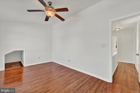 an empty room with wooden floor and fan