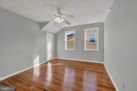 a view of an empty room with wooden floor and window
