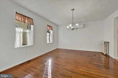a view of a room with wooden floor chandelier and windows