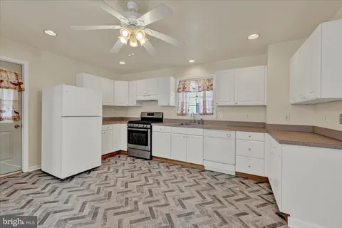 a kitchen with stainless steel appliances granite countertop a refrigerator sink and white cabinets