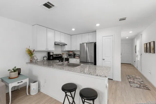 a kitchen with stainless steel appliances granite countertop a sink refrigerator and cabinets