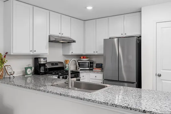 a kitchen with stainless steel appliances granite countertop a refrigerator a stove a sink and a granite counter tops