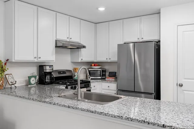 a kitchen with stainless steel appliances granite countertop a refrigerator a stove a sink and a granite counter tops