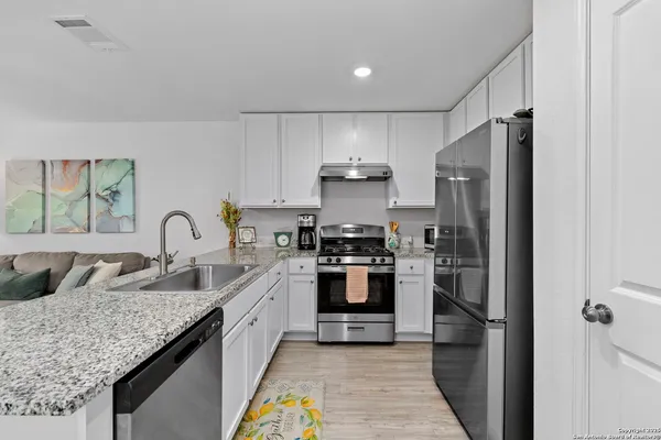 a kitchen with stainless steel appliances granite countertop a sink stove and refrigerator