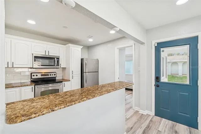 a kitchen with a refrigerator a microwave a sink and dishwasher with wooden floor