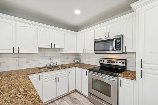 a kitchen with granite countertop a stove sink and cabinets