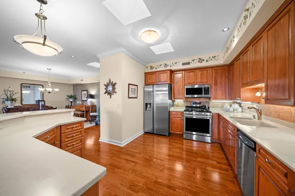 a kitchen with stainless steel appliances granite countertop a refrigerator a sink dishwasher stove and oven with wooden floor