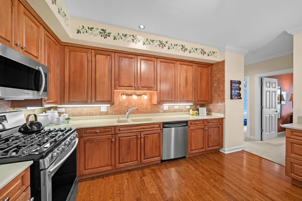 a kitchen with stainless steel appliances granite countertop a stove a sink dishwasher and a microwave oven with wooden floor