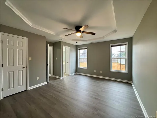 a view of an empty room with window and wooden floor