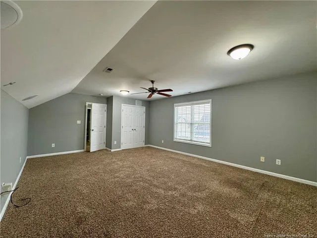 an empty room with a ceiling fan and window
