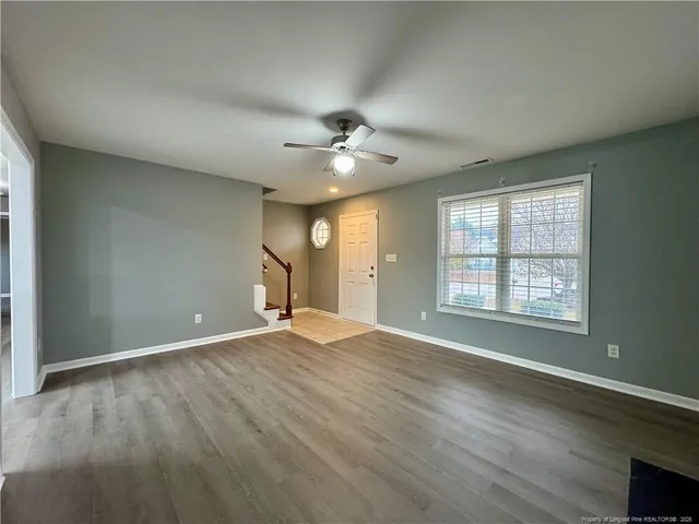 an empty room with wooden floor and windows