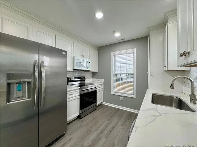 a kitchen with stainless steel appliances granite countertop a refrigerator a sink a stove and oven